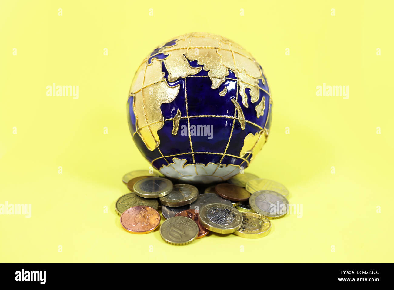 Blau und Gold Kugel auf einem Haufen aus einer Mischung von Münzen aus den USA Europa und Großbritannien sitzen Stockfoto