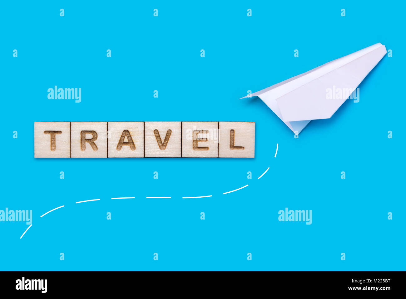 Konzept auf das Thema der Reise. Weiß origami Flugzeug auf einem blauen Hintergrund. Das Wort Reisen aus Holz Bausteine gelegt wird. Stockfoto