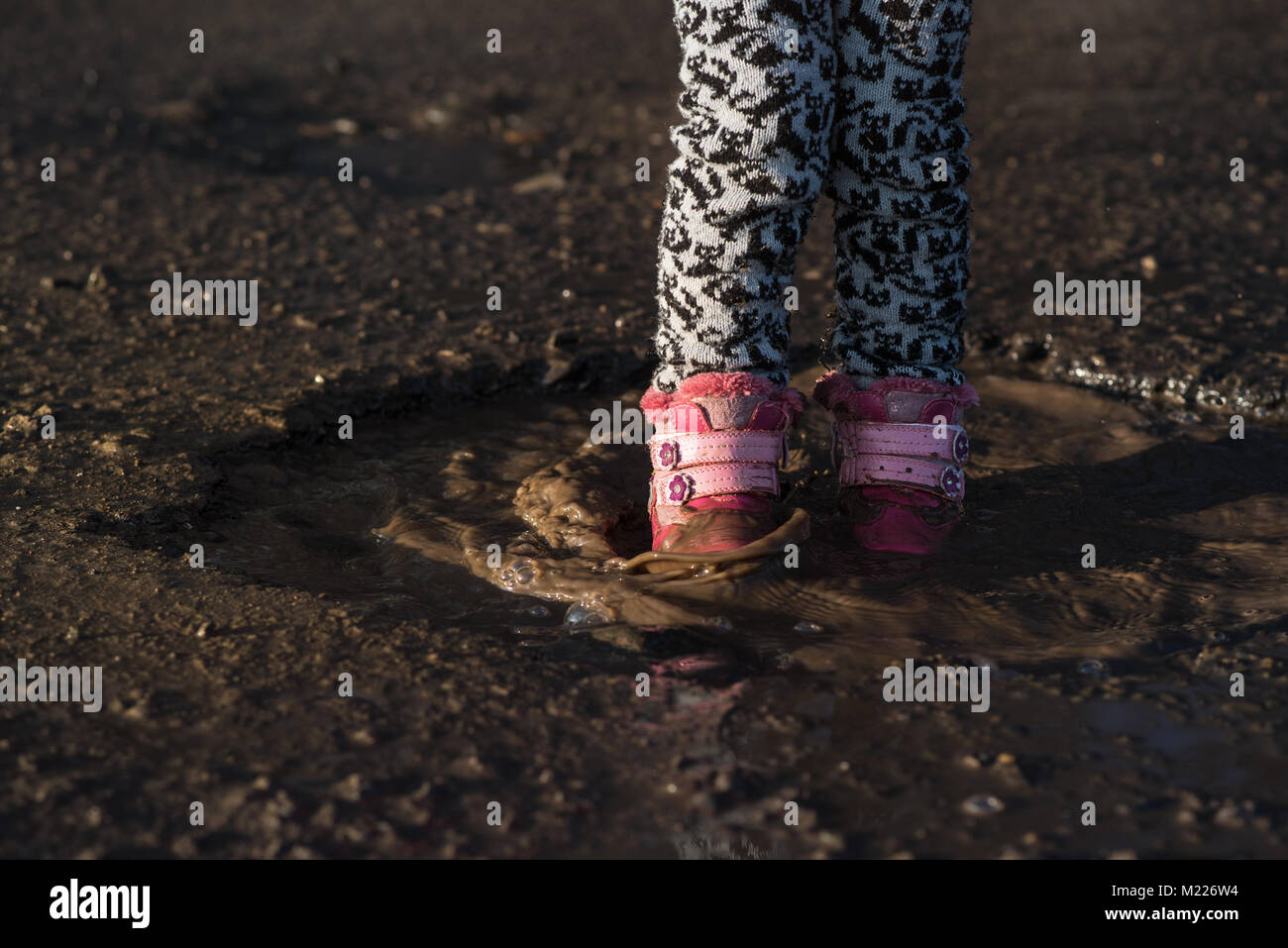 Kleines Mädchen spielt in Wasser, nass schmutzige Schuhe, in der Mitte der Pfütze, unvergessliche Momente, Unterhaltungen und. Konzept - Kind mit Vati auf Wal Stockfoto