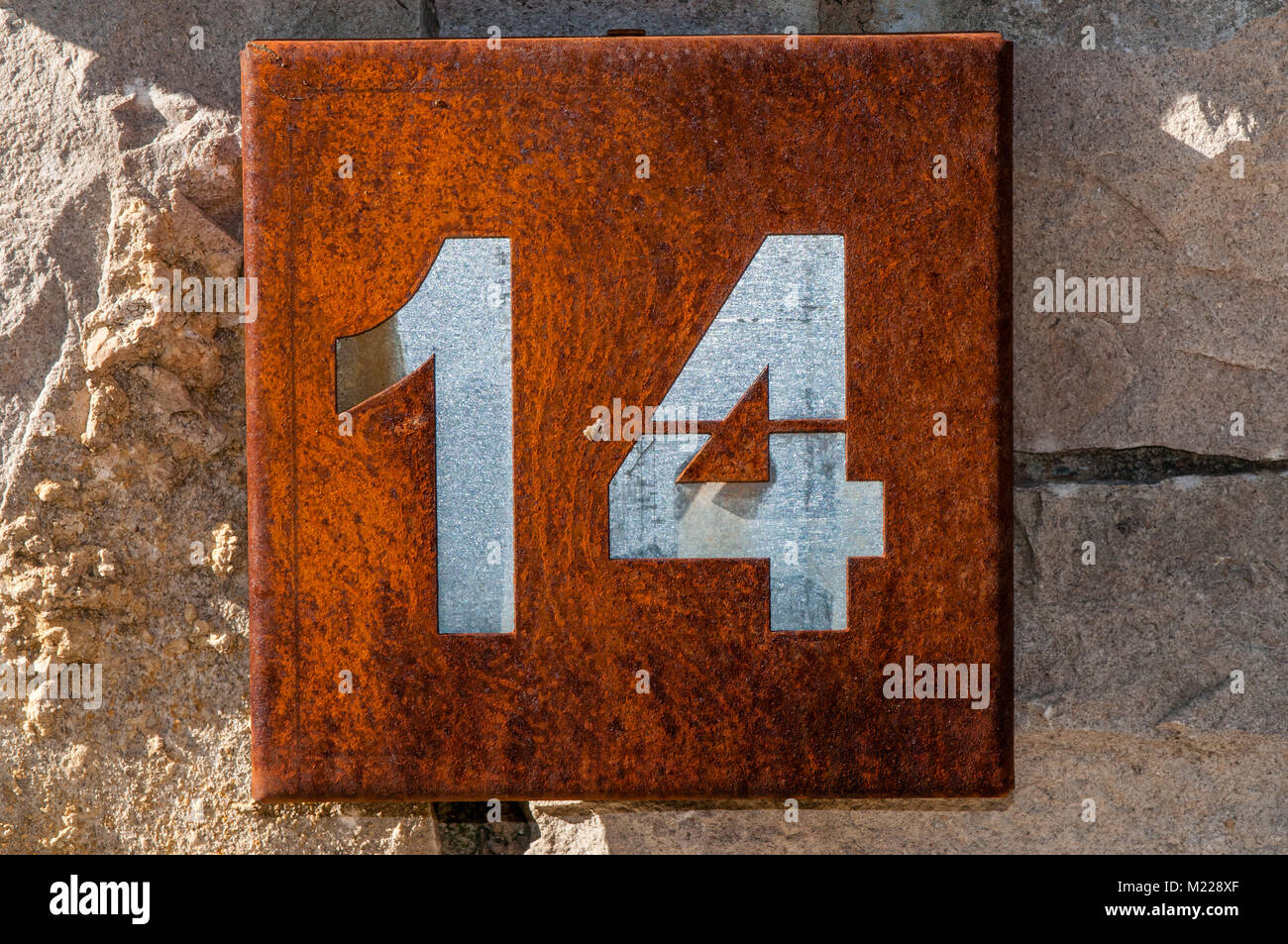 Hausnummer 14 auf eine rostige Metallplatte hangin auf einer Steinmauer, Tavertet, Katalonien, Spanien Stockfoto