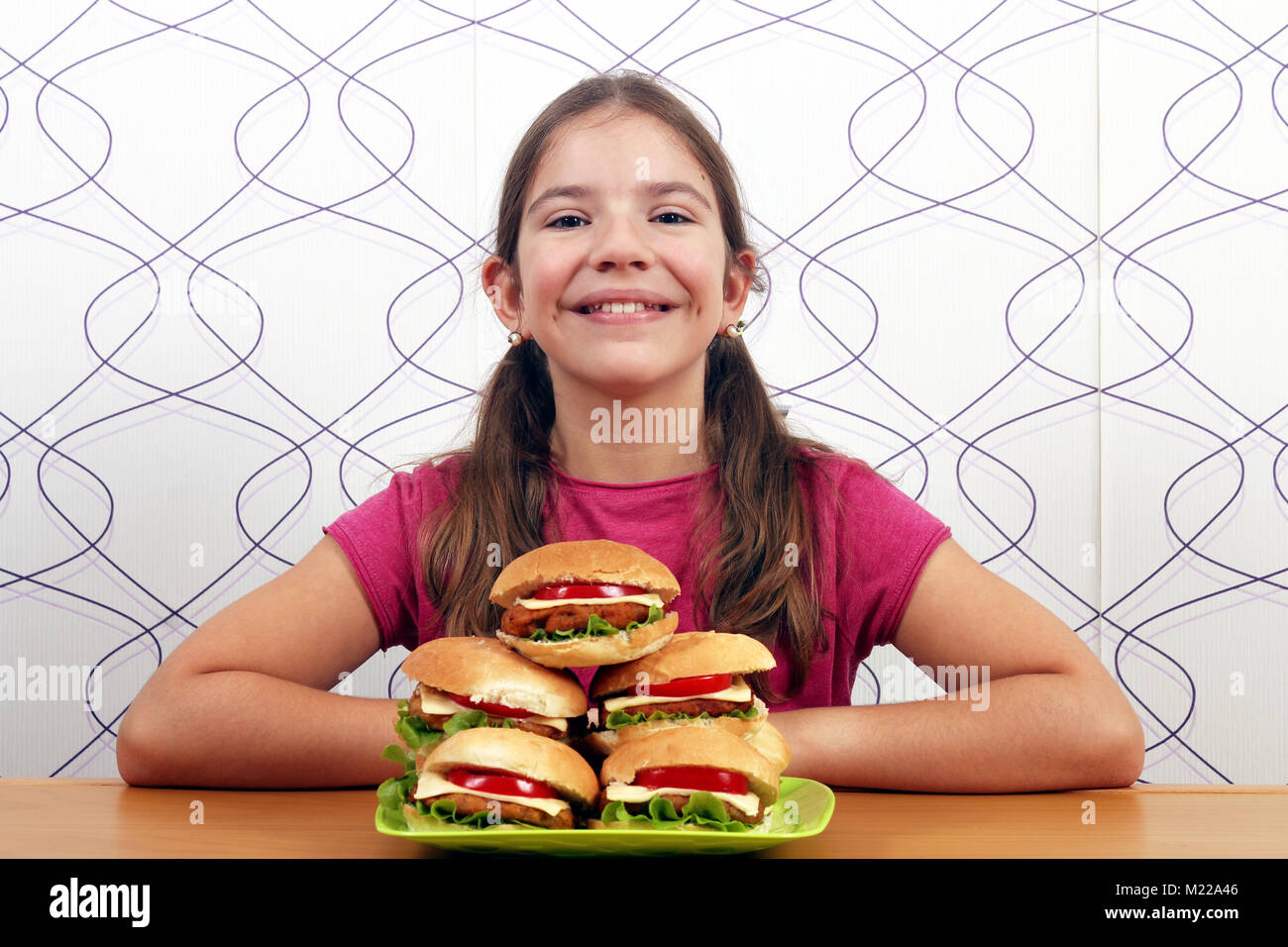 Gerne kleine Mädchen mit Hamburgern fast food Stockfoto