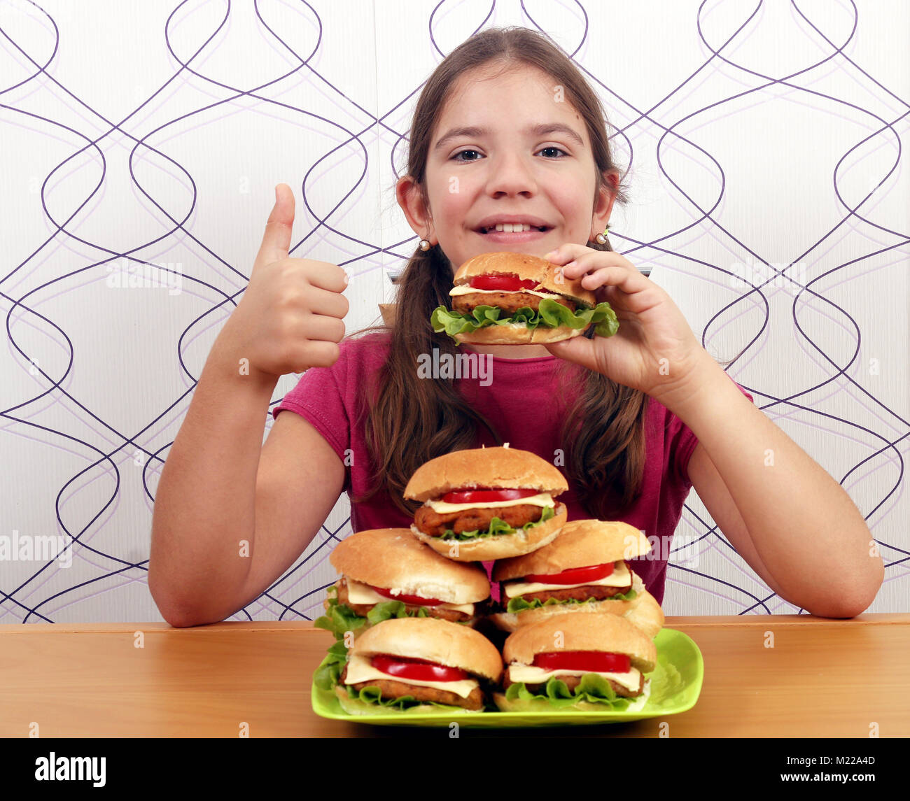 Kleines Mädchen mit Hamburger und Daumen hoch Stockfoto