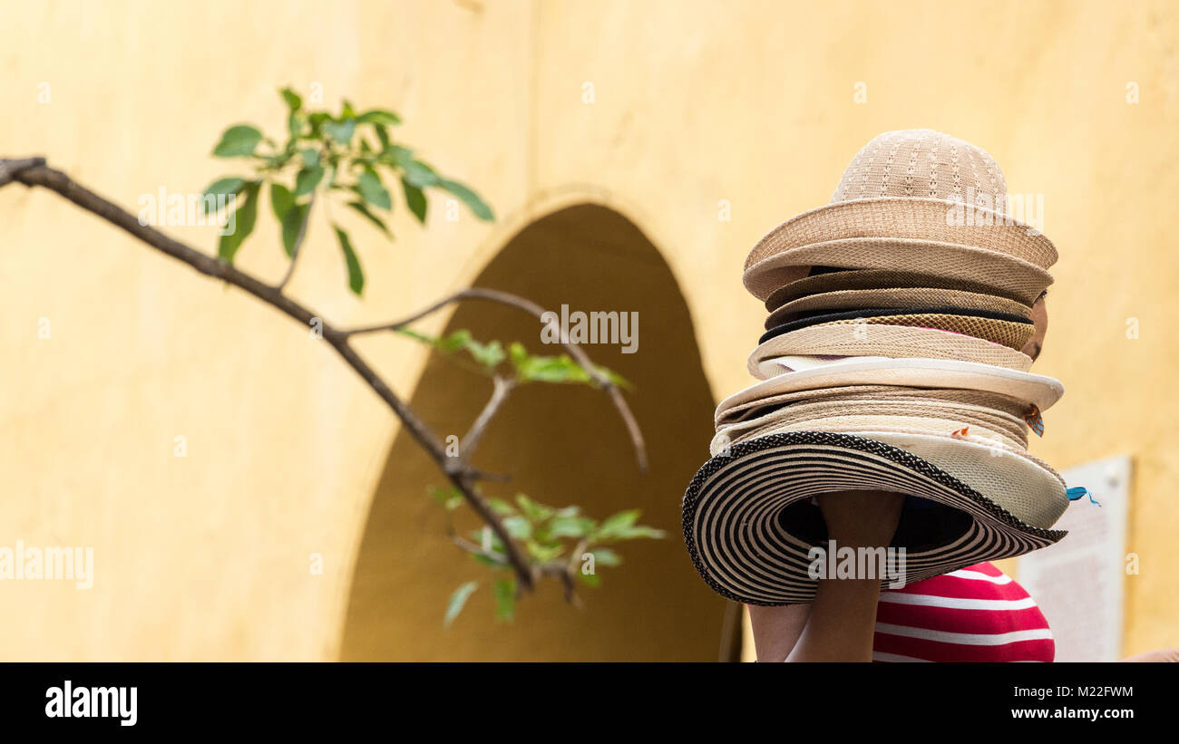 Eine weibliche Verkäufer halten und tragen einen Stapel der kolumbianischen Hüte im Torre Del Reloj Square in Cartagena, Kolumbien. Stockfoto