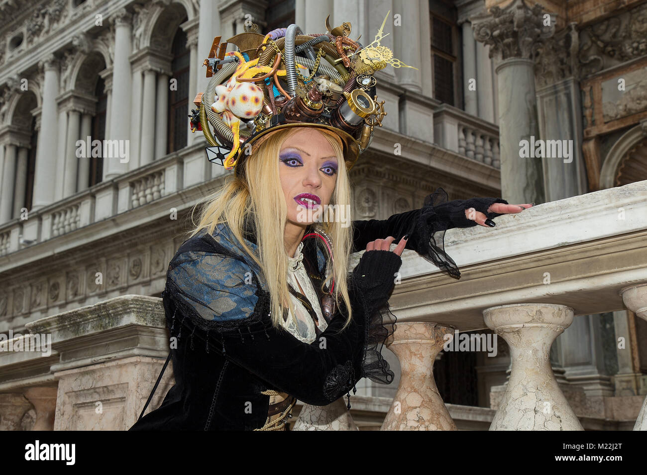 Karneval in Venedig - Vampire Portrait - Weibliche Venezianische Maske mit magischen blauen Augen, Vampir Zähne, langen blonden Haaren und einzigartige künstlerische Hut auf dem Markusplatz Stockfoto