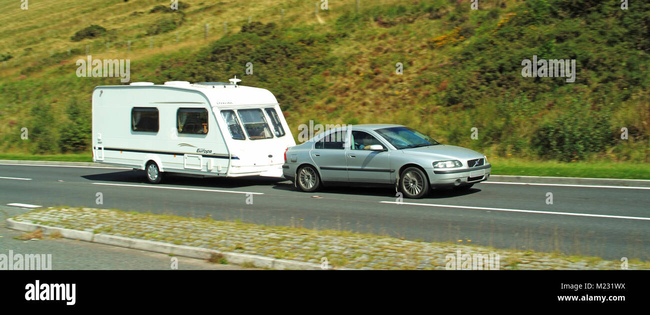 Mann fährt Auto Schleppen weißen Wohnwagen auf ländlichen malerischen Landschaft Straße im Brecon Beacons National Park Powys South Wales VEREINIGTES KÖNIGREICH Stockfoto
