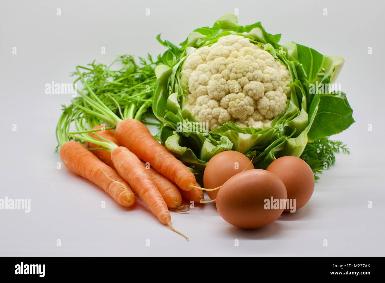 Blumenkohl, Möhren und Eier auf weißem Hintergrund Stockfoto