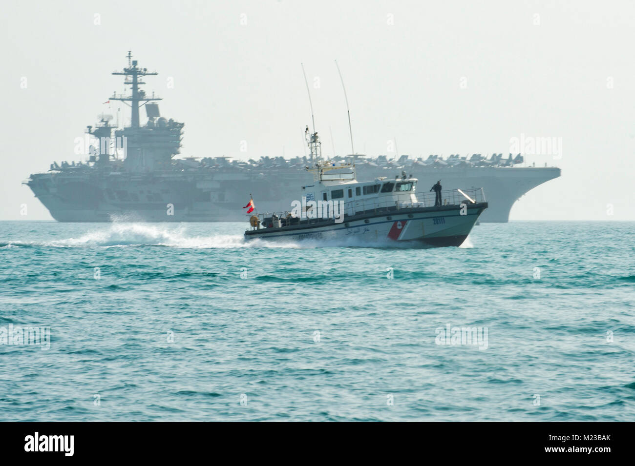 180126-N-XE 158-0087 BAHRAIN (Jan 26, 2018) eine Bahrain Coast Guard Vessel unterstützt Segler zum Kommandanten, Task Group (TG) 56.7, in High Value Asset Protection der Flugzeugträger USS Theodore Roosevelt (CVN 71) Wie es zu Khalifa Bin Salman port, Bahrain Transite zugeordnet. Theodore Roosevelt und ihre Carrier strike Group werden in den USA 5 Flotte Bereich für Maßnahmen zur Erhöhung der Sicherheit im Seeverkehr im Einsatz Verbündeten und Partnern zu beruhigen und der Freiheit der Schiffahrt und des freien Handels in der Region erhalten. (U.S. Marine Foto von Mass Communication Specialist 1. Klasse Louis R Stockfoto