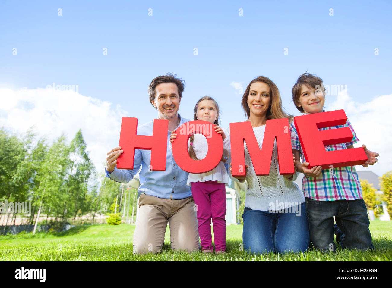 Portrait von Glücklich lächelnde Familie und ihre Kinder Holding home Buchstaben in der Nähe von Ihrem Haus Stockfoto