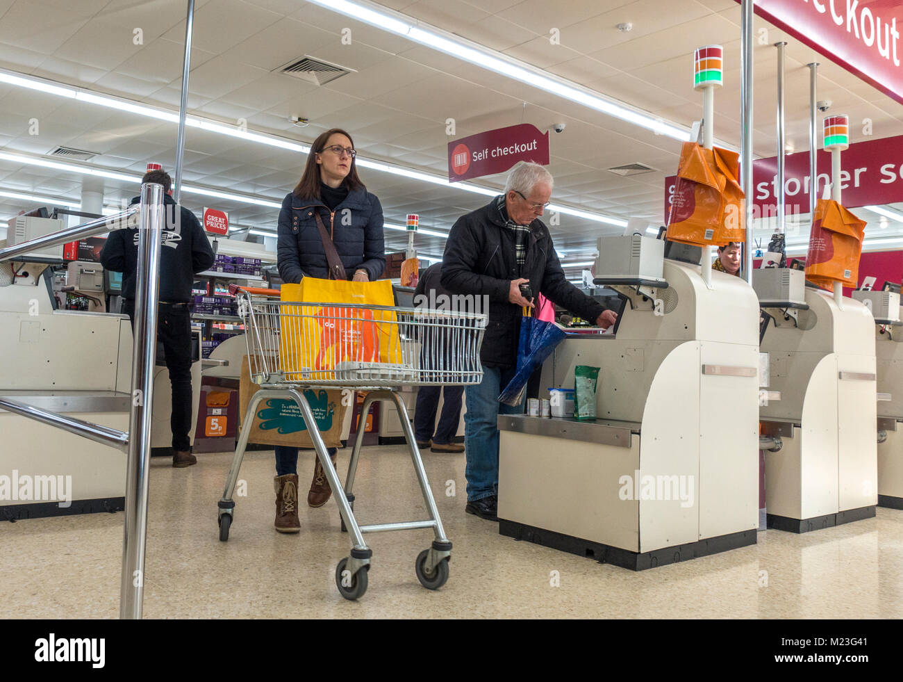 Frau mit Katze und zahlende Kunden für Ihren Einkauf an der Kasse von Sainsbury's Supermarkt in Bourne, Lincolnshire, England, UK. Stockfoto