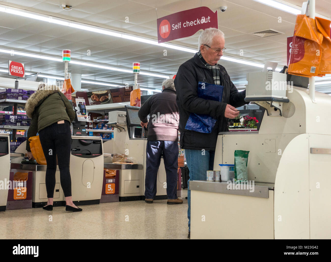 Drei Kunden zahlen für ihre Einkaufsmöglichkeiten im Self Checkout Bereich von Sainsbury's Supermarkt in Bourne, Lincolnshire, England, UK. Stockfoto