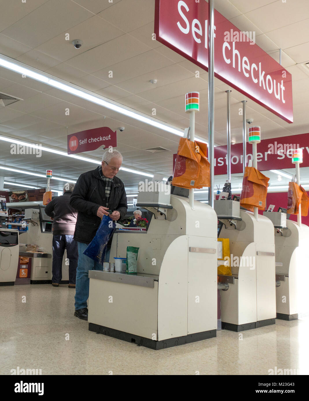 Ältere Männer/Männer zahlende Kunden für Ihren Einkauf an der Kasse von Sainsbury's Supermarkt in Bourne, Lincolnshire, England, UK. Stockfoto