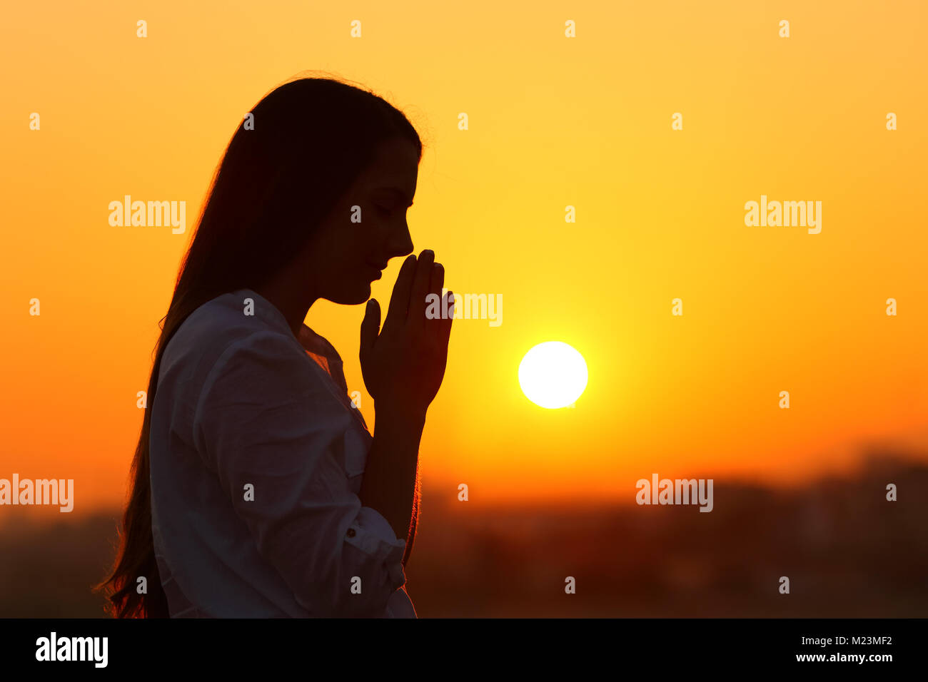 Seitenansicht Hintergrundlicht Porträt einer Frau Silhouette bei Sonnenuntergang beten Stockfoto