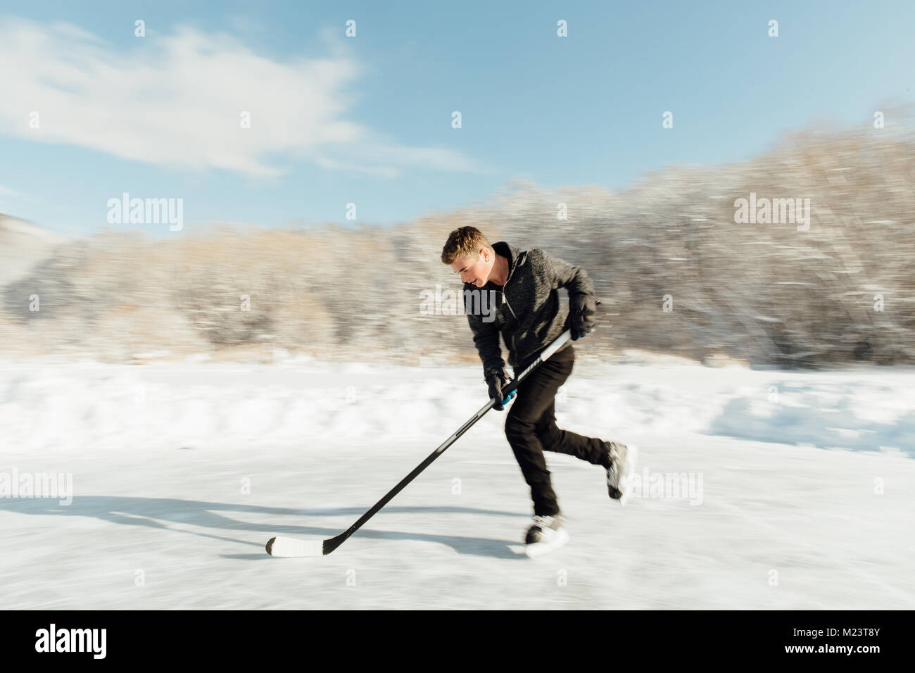 Mann spielt Eishockey auf einem zugefrorenen See Stockfoto