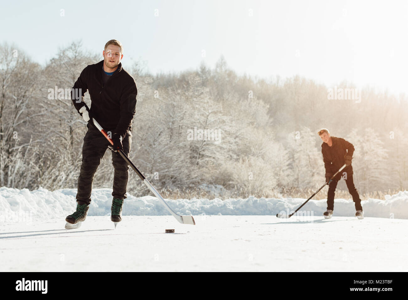 Zwei Männer spielen Eishockey auf einem zugefrorenen See Stockfoto