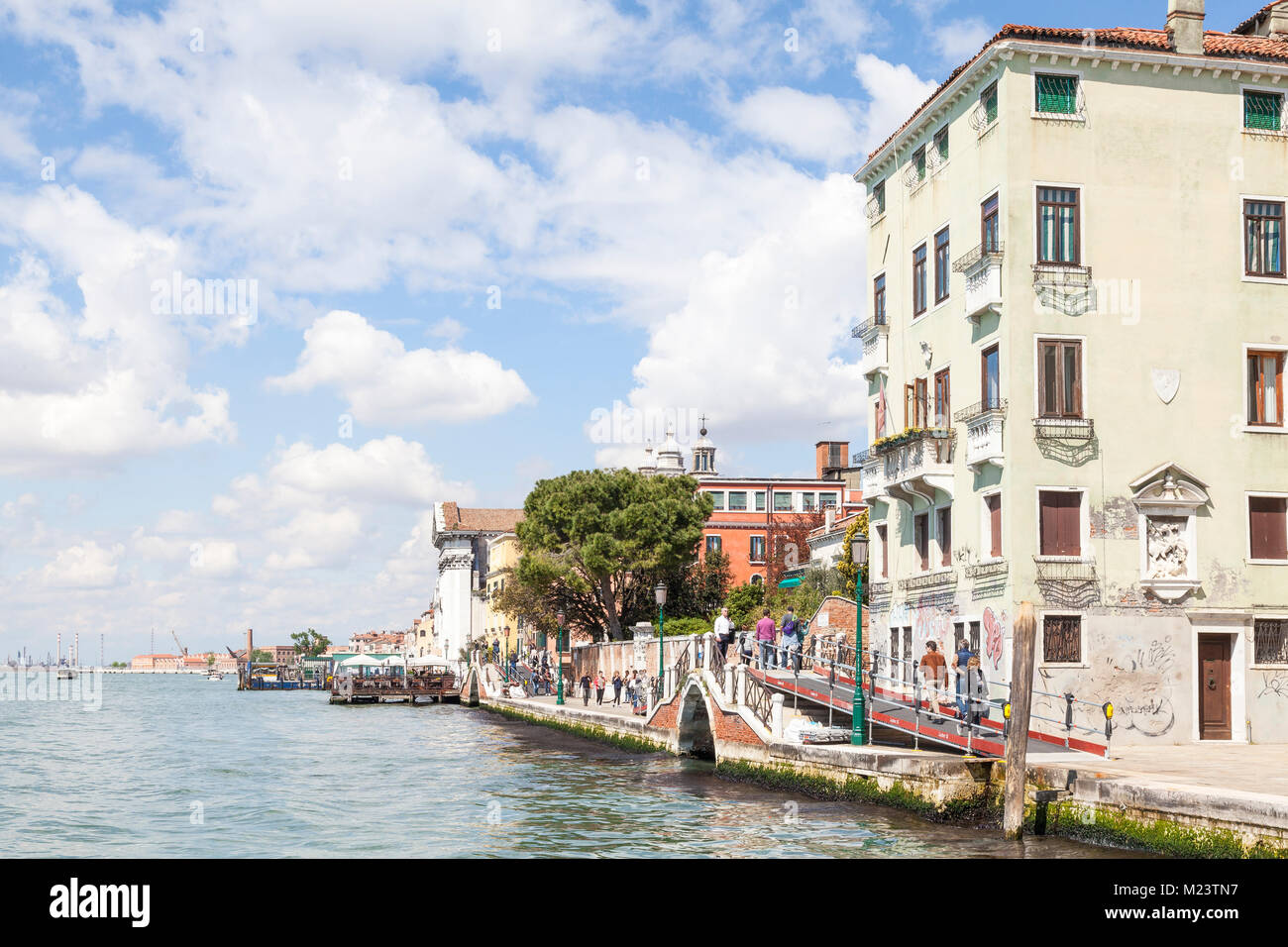 Ein Blick hinunter vom Zattere, Dorsoduro Venedig, Venetien, Italien mit Menschen zu Fuß entlang der Fondamenta entlang des Canale della Giudecca. Bewölkt blauer Himmel Stockfoto