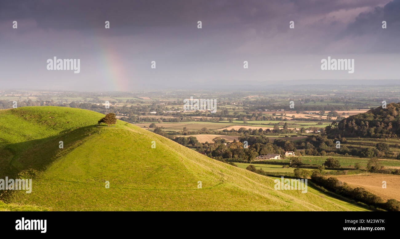 Morgen leuchtet die Landschaft der Somerset Levels und wirft einen Regenbogen an Parrock Hill, von Corton Beacon Hill im Süden von Somerset gesehen, Stockfoto