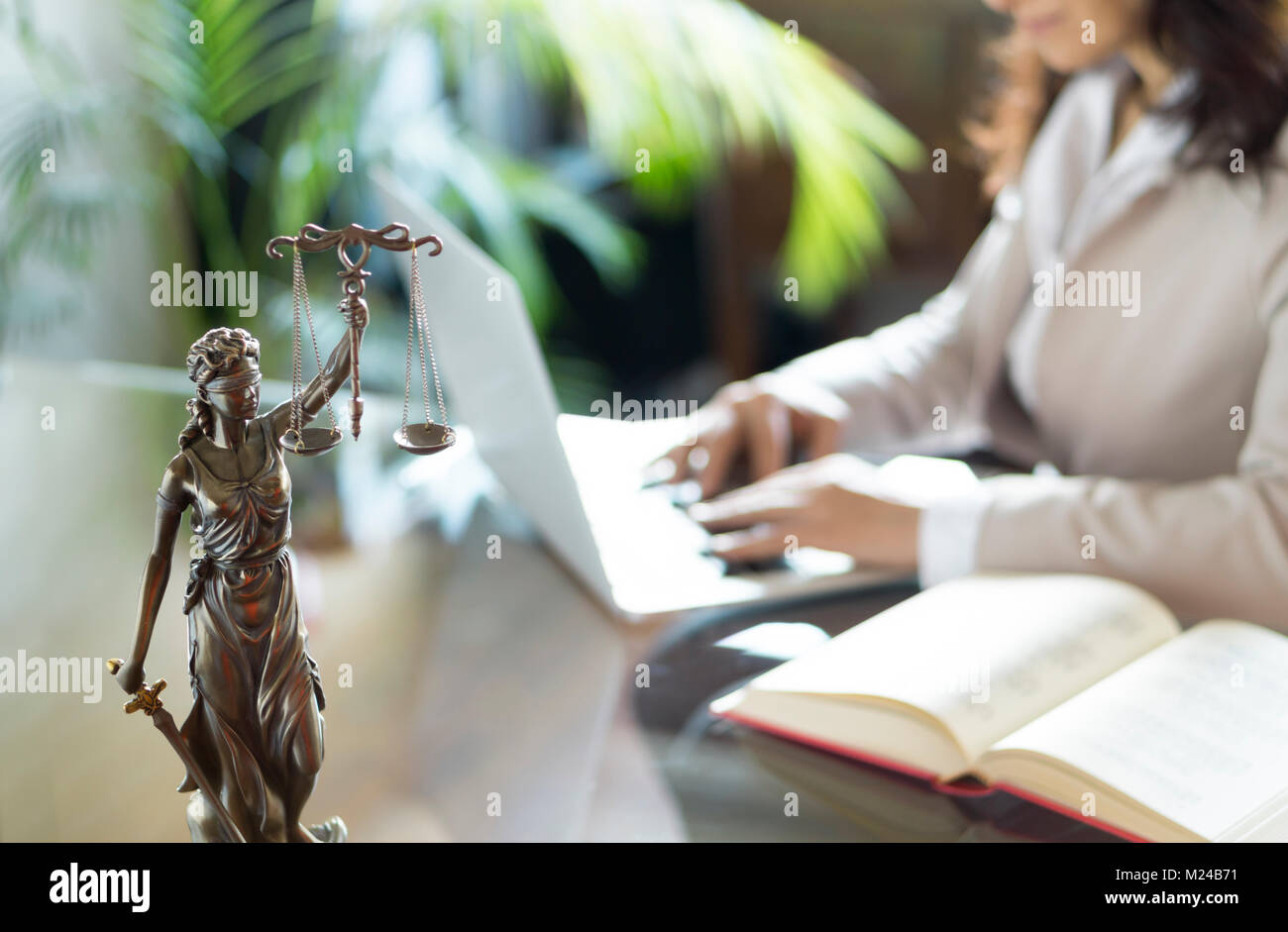 Rechtsanwalt Büro. Statue von Gerechtigkeit mit Waagen und Rechtsanwalt, der an einem Notebook arbeitet. Juristische Recht, Beratung und Gerechtigkeit Konzept Stockfoto