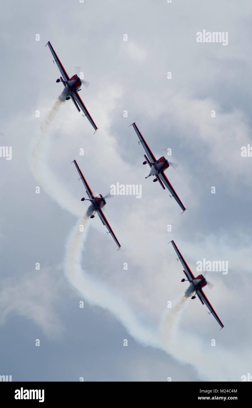 Die Blades, britische zivile Kunstflugstaffel. Fliegen in Formation mit weißer Rauch auf. 4 Extra 300 LPs in Dawlish Air Show, South Devon, Großbritannien. Stockfoto