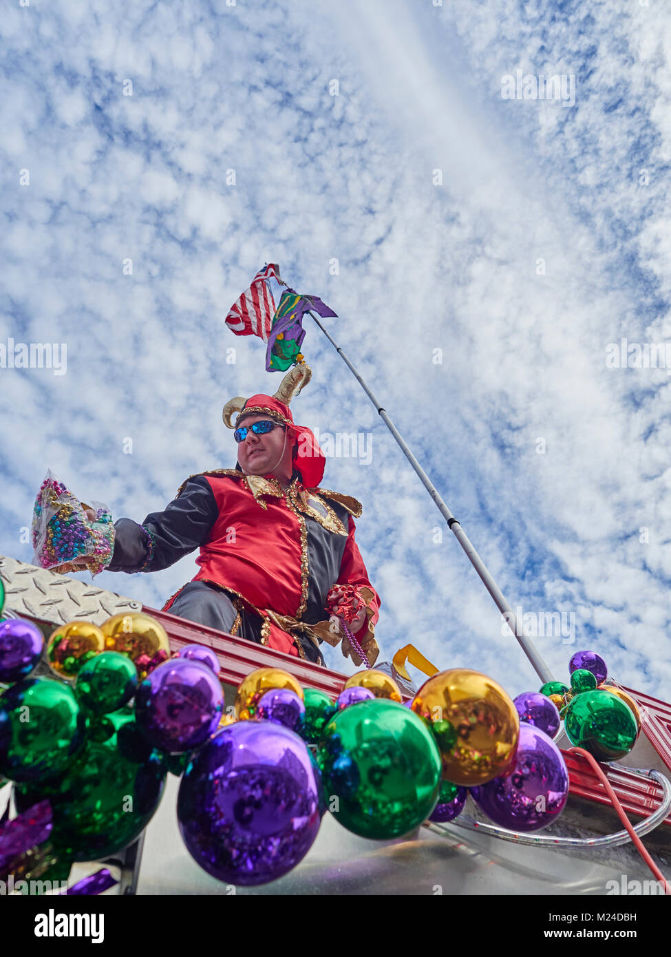 Mardi Gras jester auf einem Löschfahrzeug mit Mardi Gras Perlen dekoriert wirft eine Handvoll Perlen zu einer Masse an der Feier in Montgomery Alabama, USA. Stockfoto