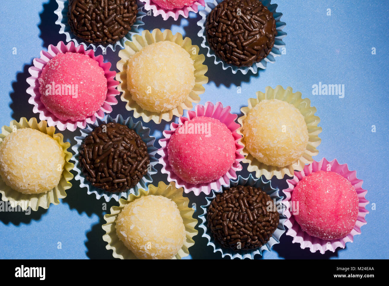 Brasilianische Spezialitäten: Brigadeiro, Beijinho und Bicho de Pe. Kindergeburtstag. Gemeinkosten der Süßigkeit, die Kugel auf blauen Tabelle. Stockfoto