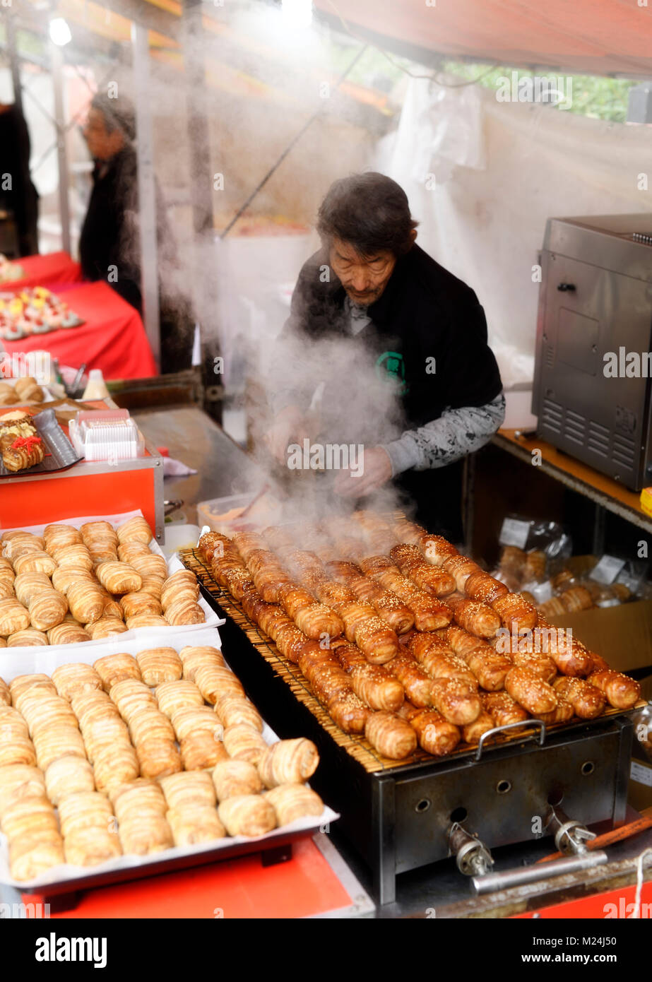 Street Food Anbieter Verkauf von gegrilltem Speck umwickelt Reisbällchen, Nikumaki Onigiri, Japanisch Street Food Markt in Kyoto, Japan Stockfoto