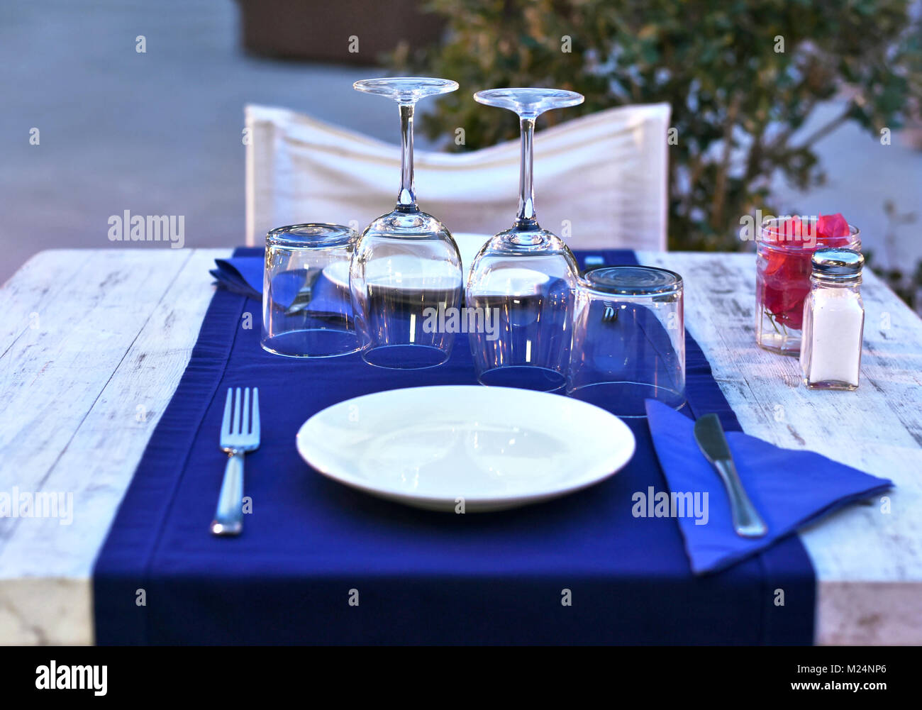 Tisch für zwei, Holztisch mit Tisch und weiße Platten. Wein, Gläser, Besteck und Tischdecke, ein romantisches Abendessen Szene. Stockfoto