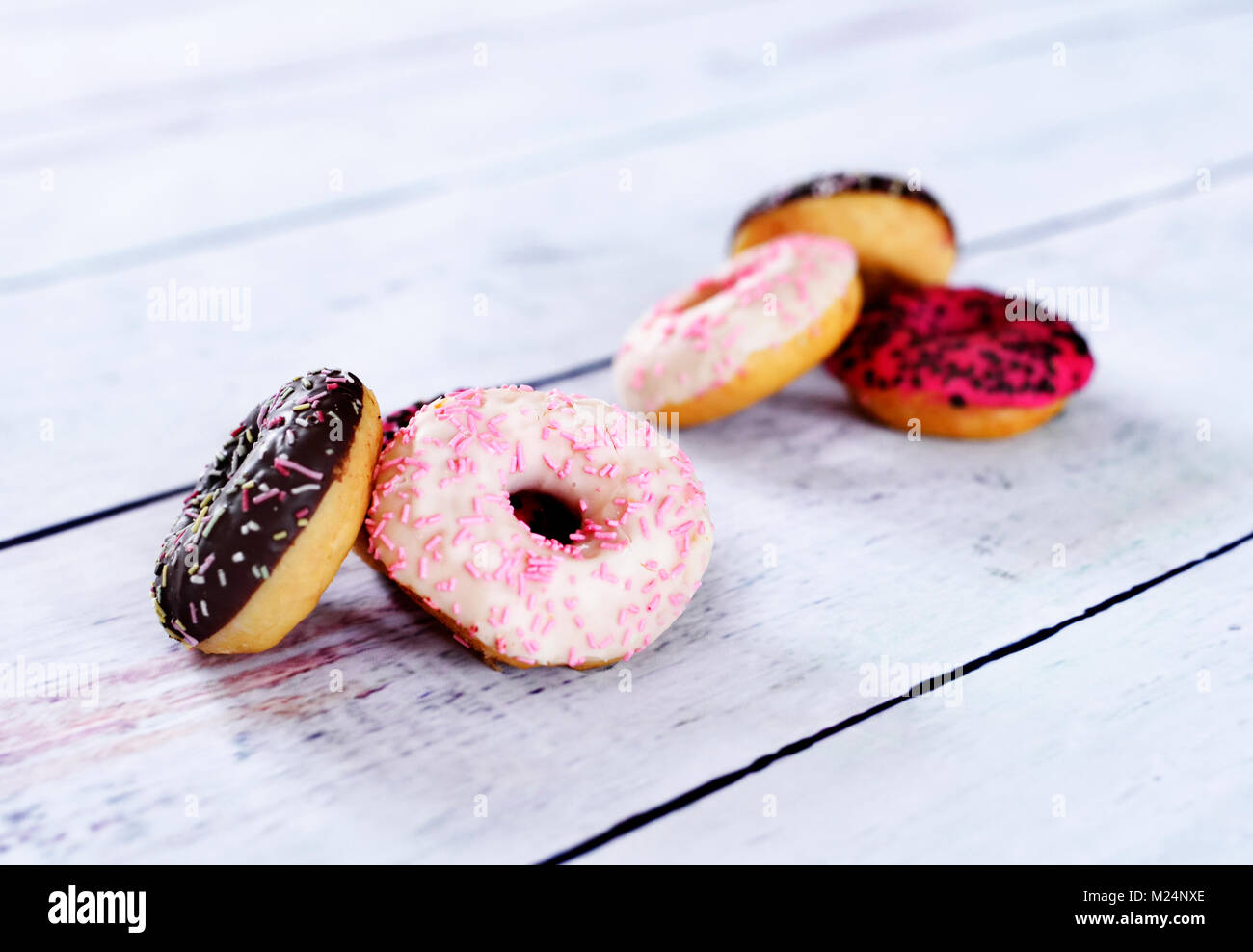 Delicious Doughnuts mit Glasur oder Vereisung und Streuseln. Variation von frischen Donuts auf einem weißen Holztisch. Anordnung mit kopieren. Stockfoto