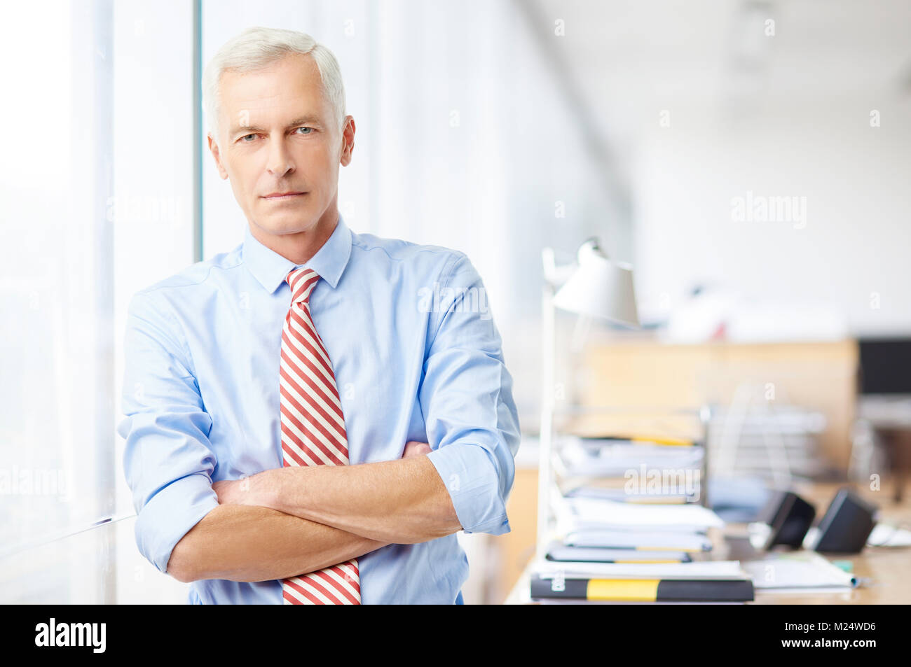 Ein Executive Sales Manager mit Waffen im Büro gekreuzt und Kamera. Stockfoto