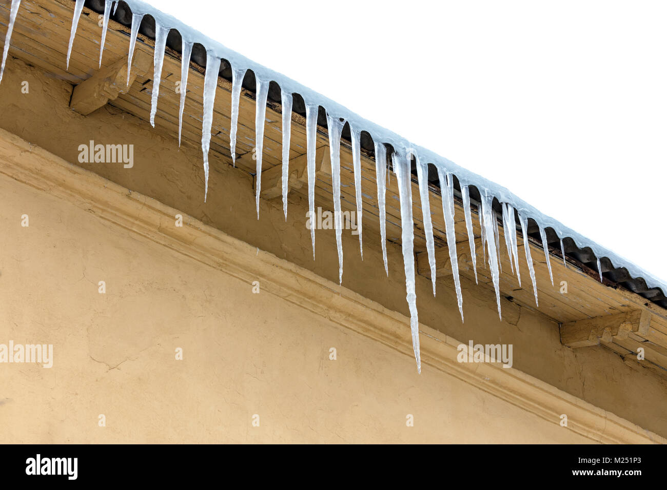 Altes haus dach, bei der die Zeile der Eiszapfen gegen Winter Himmel Hintergrund Stockfoto