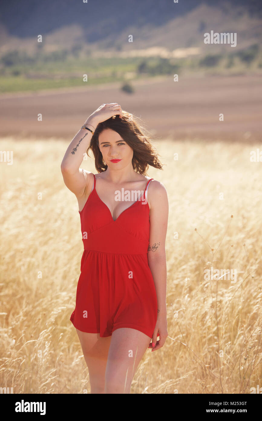 Schöne brünette Mädchen im roten Kleid auf dem Land Stockfoto