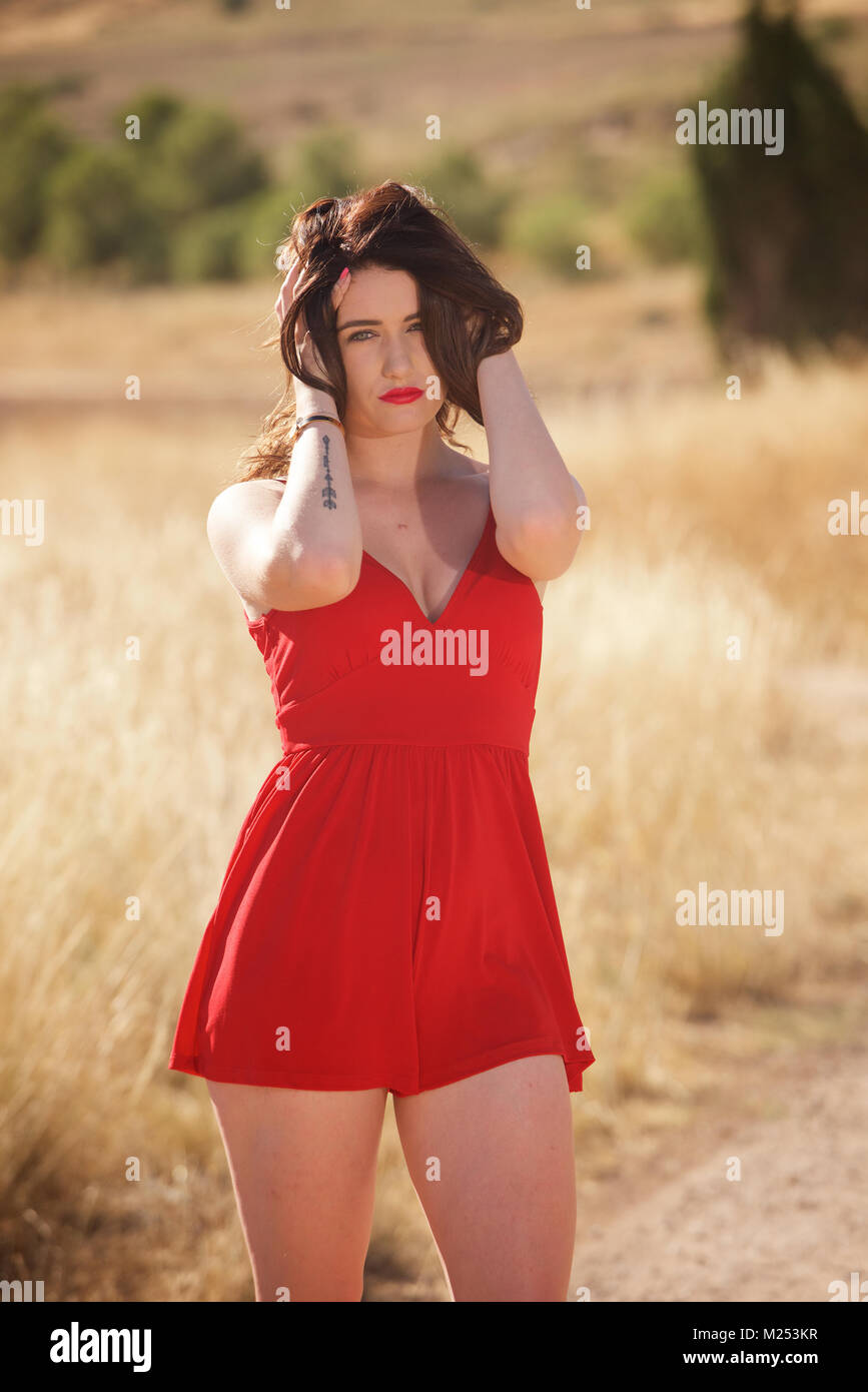 Schöne brünette Mädchen im roten Kleid auf dem Land Stockfoto