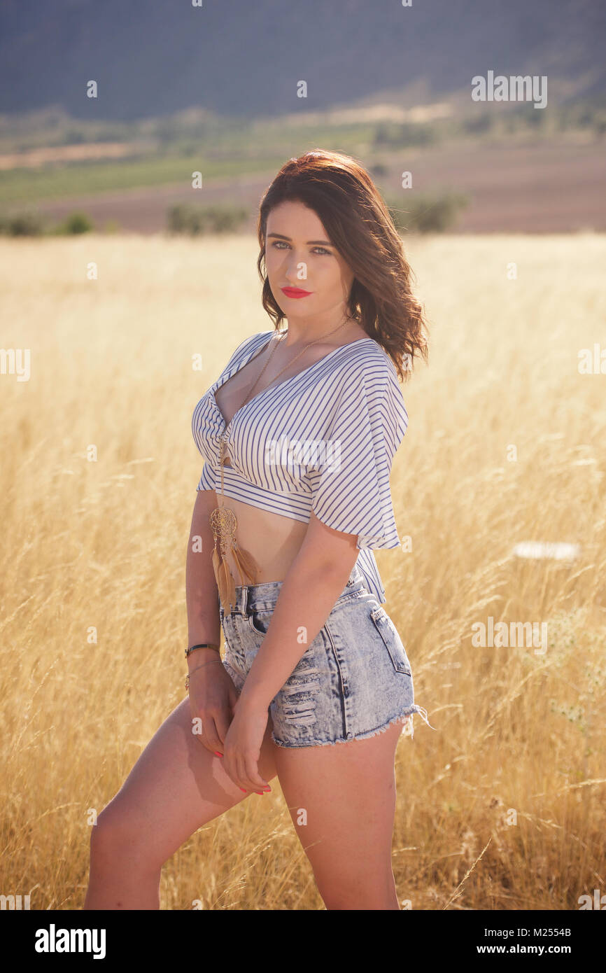 Schöne Mädchen tragen Denim Shorts und Top in der Landschaft Stockfoto