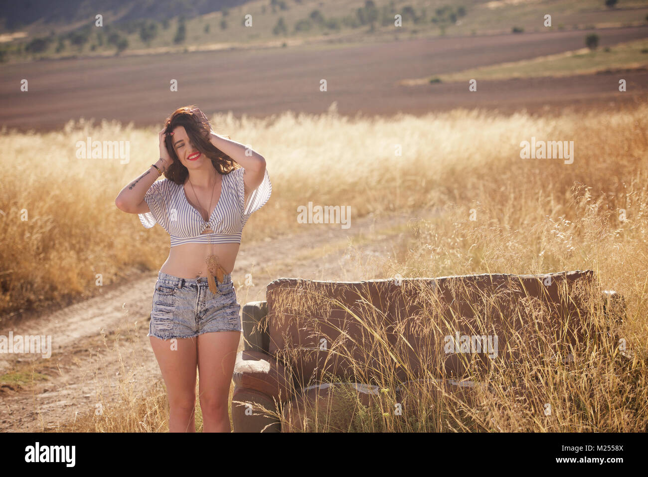 Schöne Mädchen tragen Denim Shorts und Top in der Landschaft Stockfoto