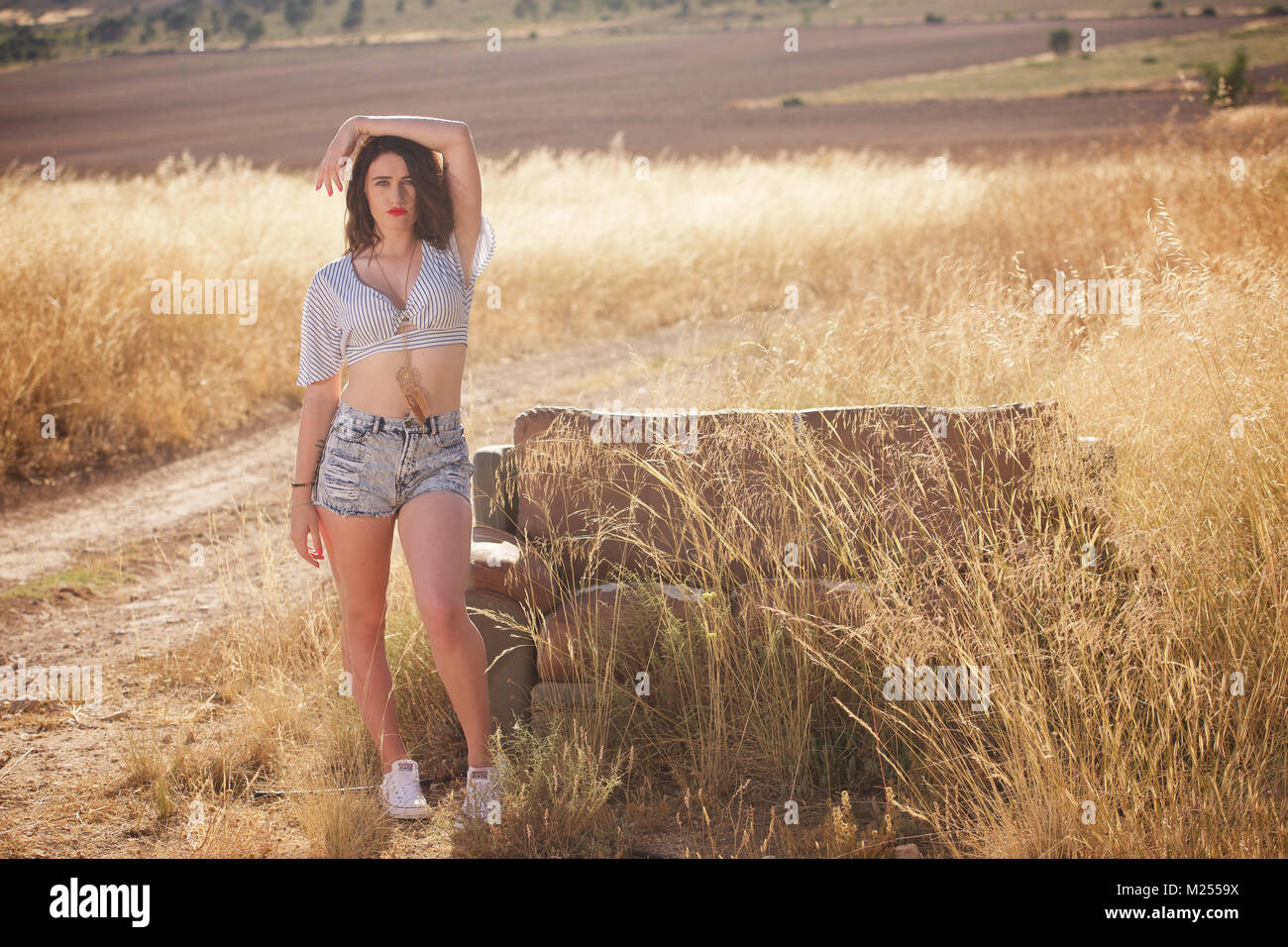 Schöne Mädchen tragen Denim Shorts und Top in der Landschaft Stockfoto