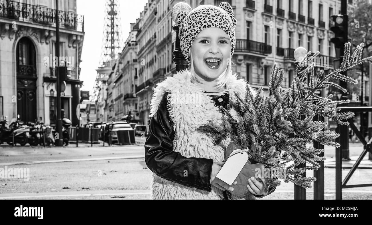 Kochend heiß trendige Winter in Paris. In voller Länge Portrait von lächelnden moderne Kind mit Weihnachtsbaum in Paris, Frankreich Stockfoto