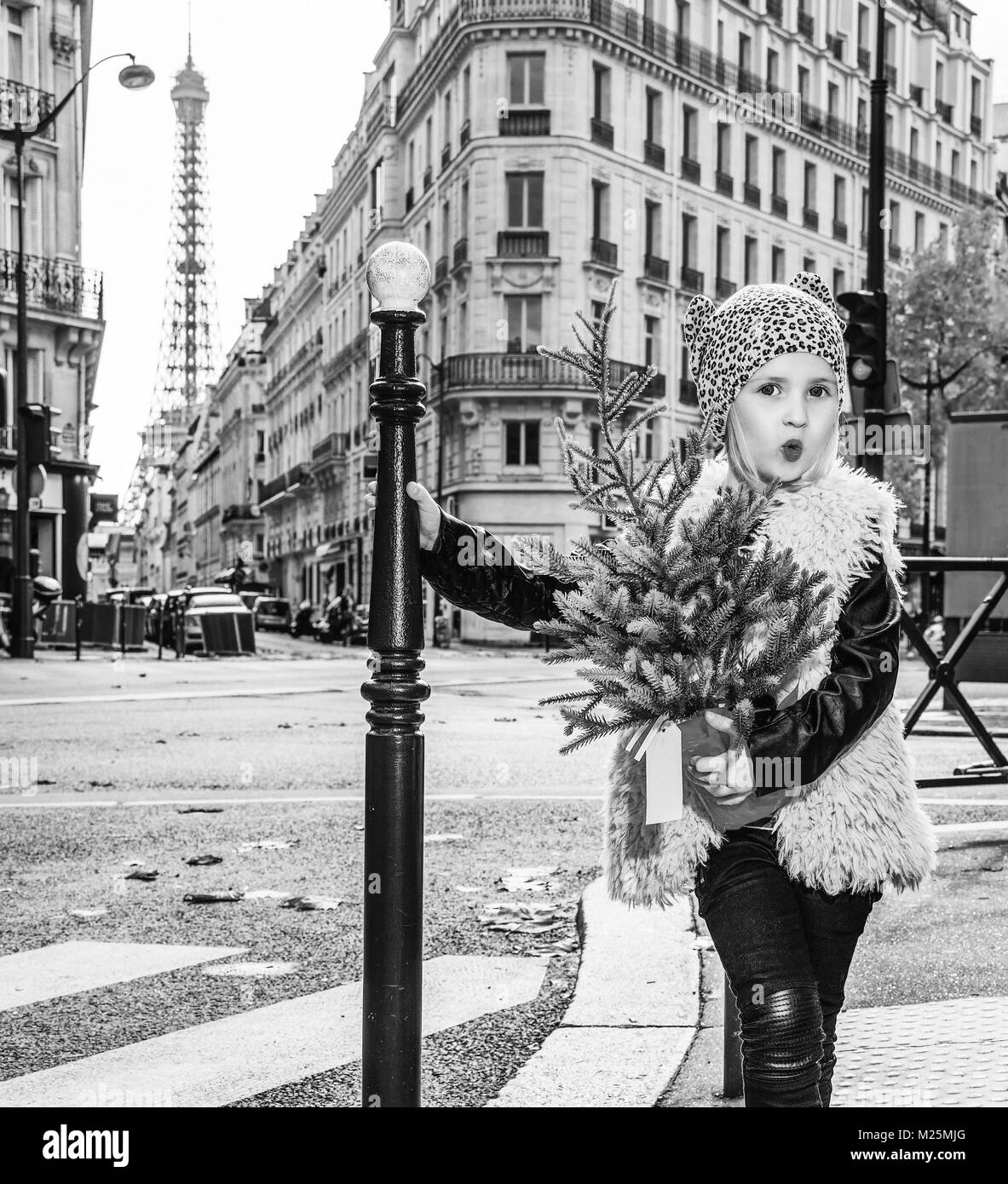 Kochend heiß trendige Winter in Paris. In voller Länge Portrait von modernen lustig Kind mit Weihnachtsbaum in Paris, Frankreich Stockfoto