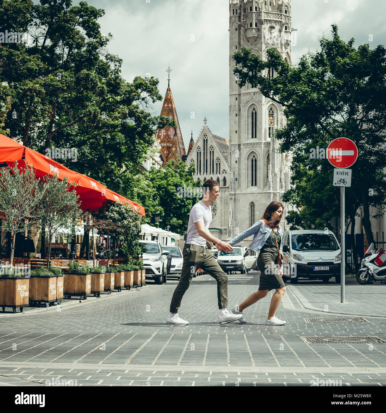 Die in voller Länge auf Das liebende Paar Touristen halten sich an den Händen, während die Kreuzung auf dem Hintergrund der St. Matthew's Kathedrale in Budapest, Ungarn. Stockfoto