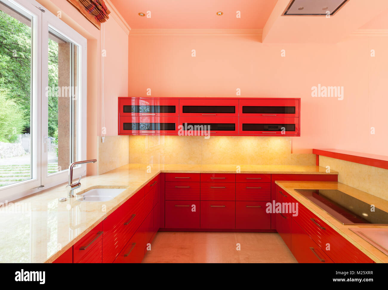 In einer luxuriösen Villa mit einem roten Küche und ein Fenster an der Seite. Alles leer, bereit für den Einsatz. Es ist eine besonders moderne Umgebung Stockfoto