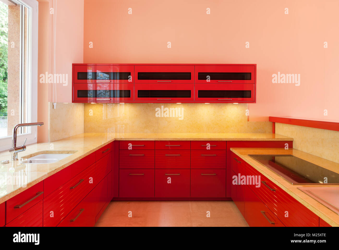 In einer luxuriösen Villa mit einem roten Küche und ein Fenster an der Seite. Alles leer, bereit für den Einsatz. Es ist eine besonders moderne Umgebung Stockfoto