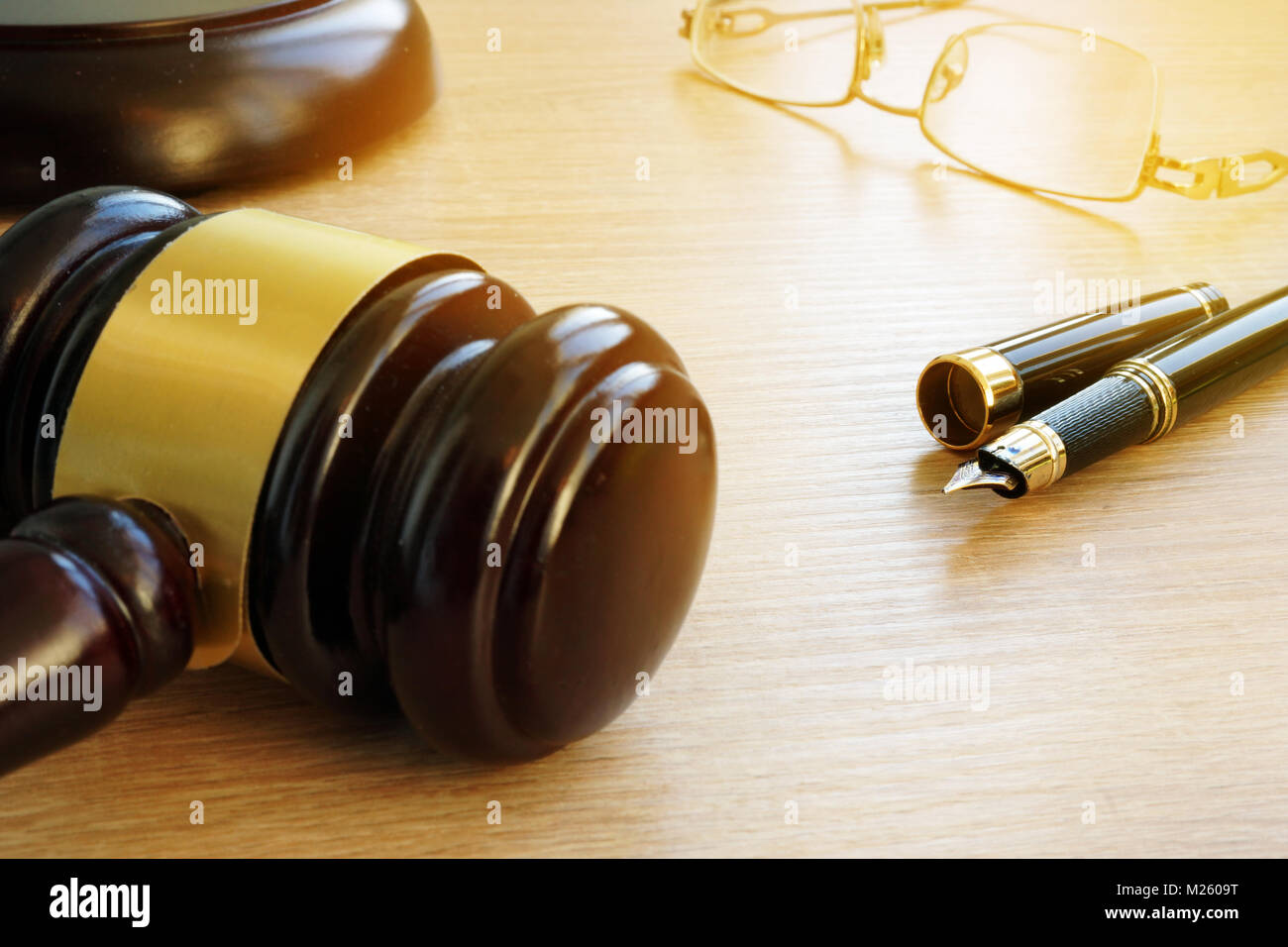 Gesetz Konzept. Richter Hammer, Pen und Gläser auf einem hölzernen Schreibtisch in einem Gerichtssaal. Stockfoto