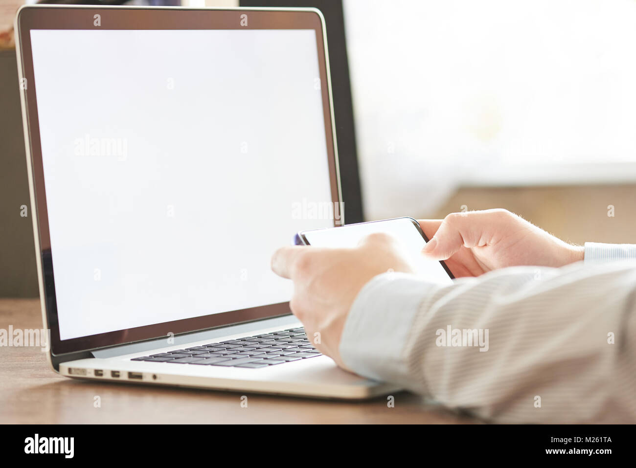 Online Studie Mock-up. Mann mit Smartphone mit Laptop auf dem Schreibtisch Stockfoto