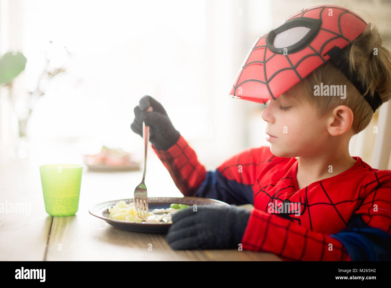 Skandinavische junge Essen sein Mittagessen in einem Spider Man Kostüm. Stockfoto