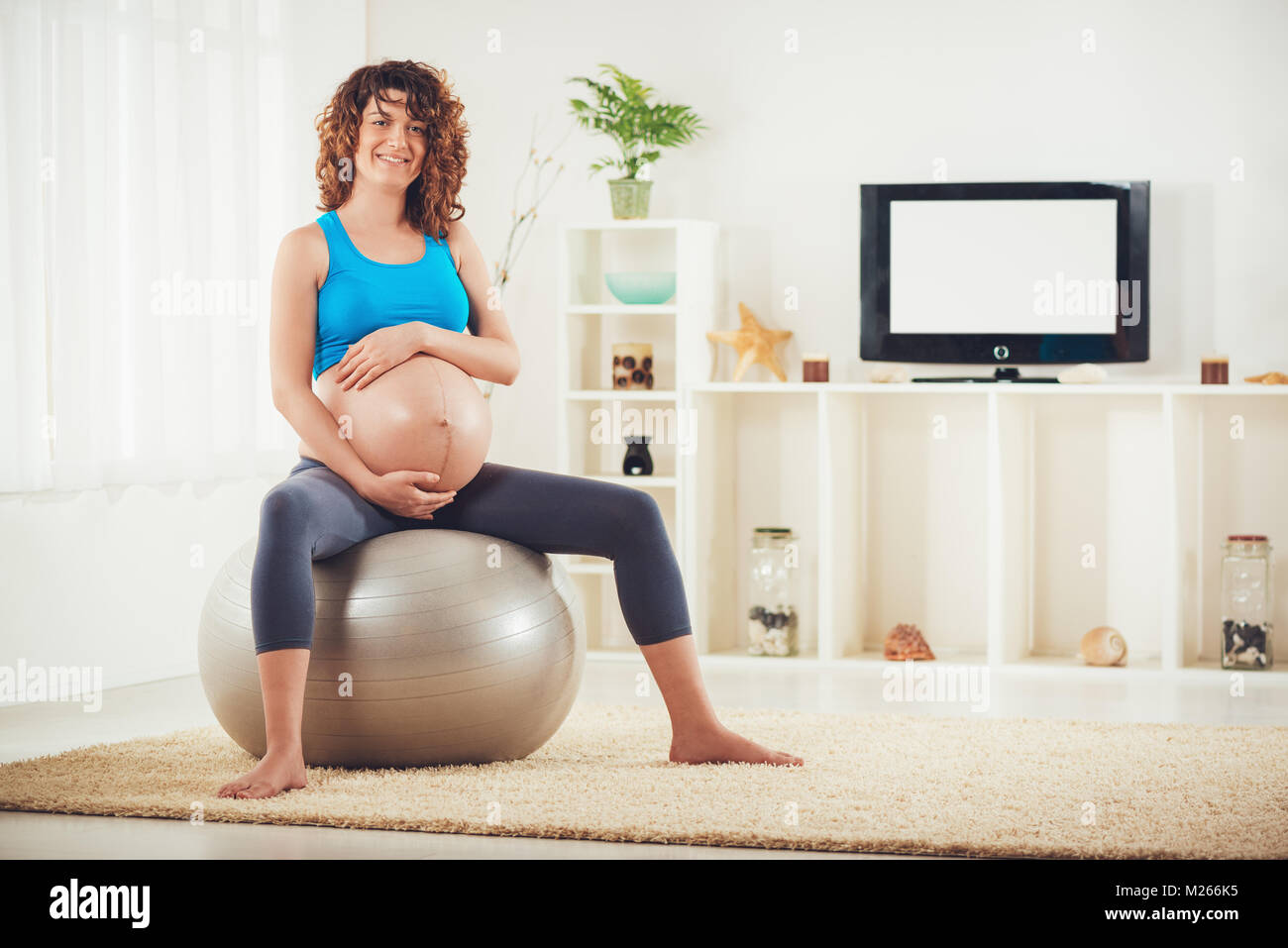 Schöne junge schwangere Frau sitzt auf einem Fitness Ball und entspannen im Hause. Stockfoto