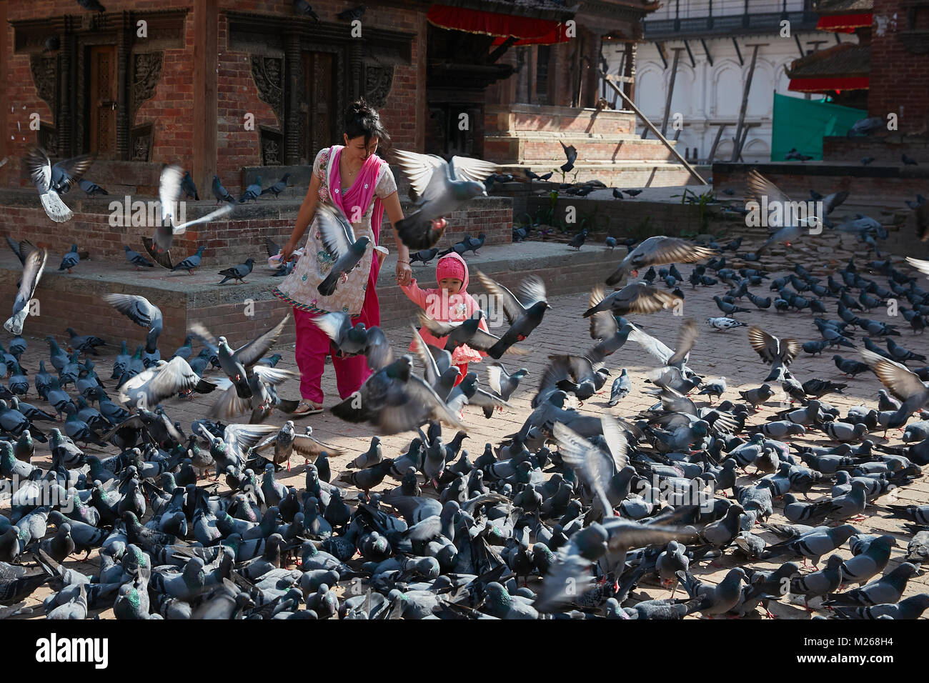 Mutter und Kleinkind Mädchen zu Fuß am Durbar Square, Kathmandu, Nepal von fliegenden Straße Tauben umgeben Stockfoto