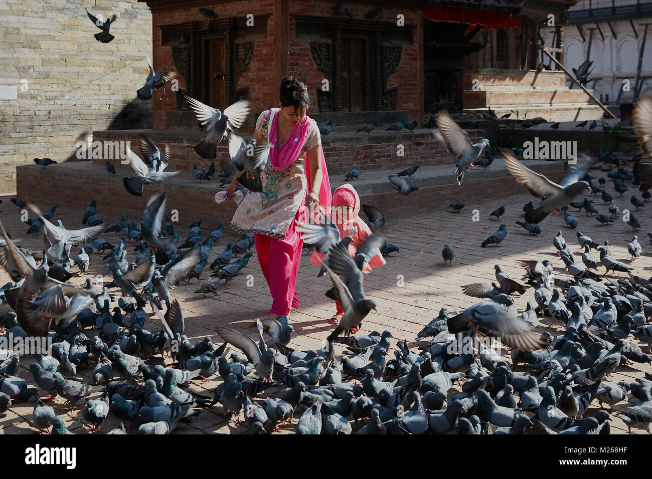 Mutter und Kleinkind Mädchen zu Fuß am Durbar Square, Kathmandu, Nepal von fliegenden Straße Tauben umgeben Stockfoto