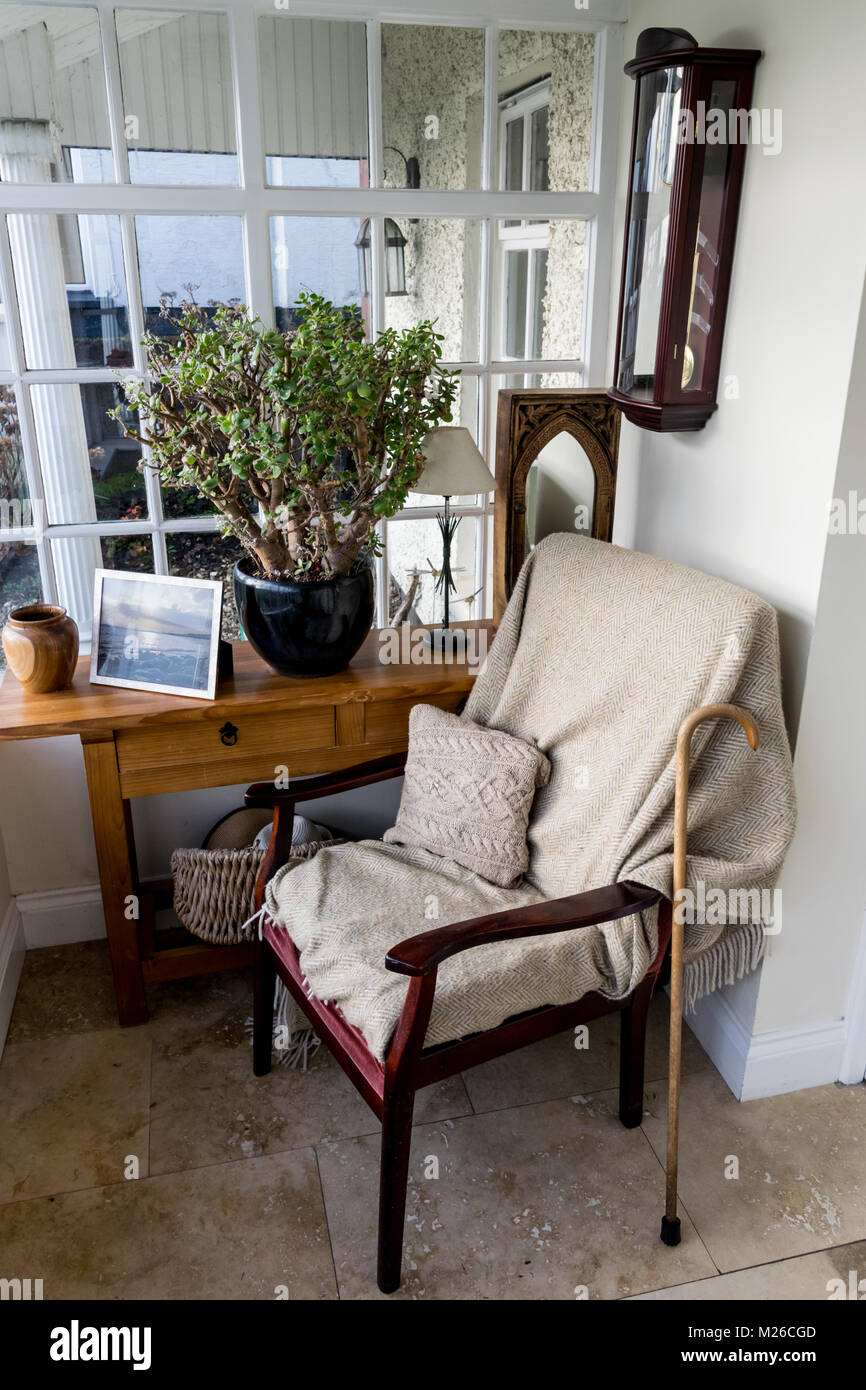 Leeren Sessel auf einer Veranda mit einer Decke Deckenkehlung und einem Stock gegen den Stuhl ruht. Stockfoto