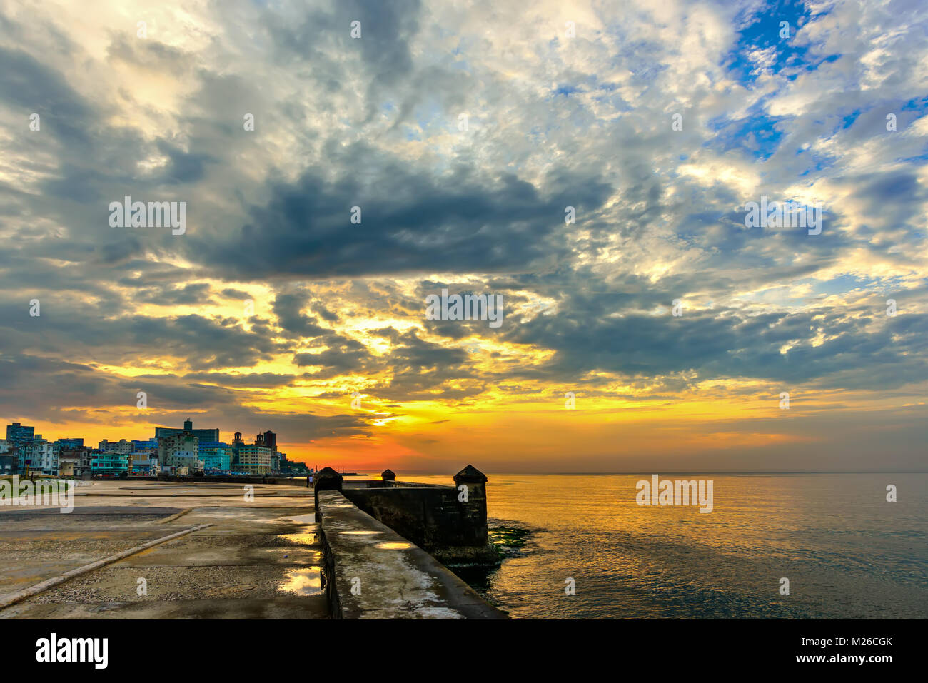 Eine köstliche orange Sonnenuntergang mit üppigen blauen Wolken über die historischen Gebäude von Havanna auf dem Malecon Waterfront, in der Nähe des Meeres Stockfoto