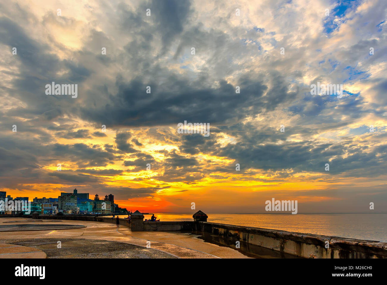 Eine köstliche orange Sonnenuntergang mit üppigen blauen Wolken über die historischen Gebäude von Havanna auf dem Malecon Waterfront, in der Nähe des Meeres Stockfoto