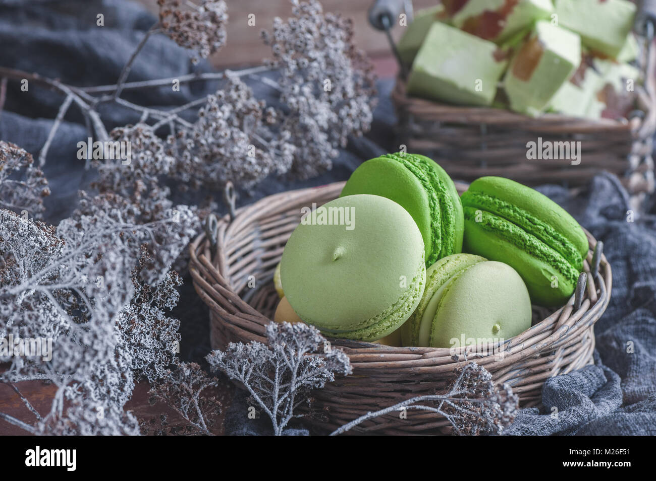 Frisch gebackene farbige Makronen in Weidenkorb mit Griffen mit kleinen ...
