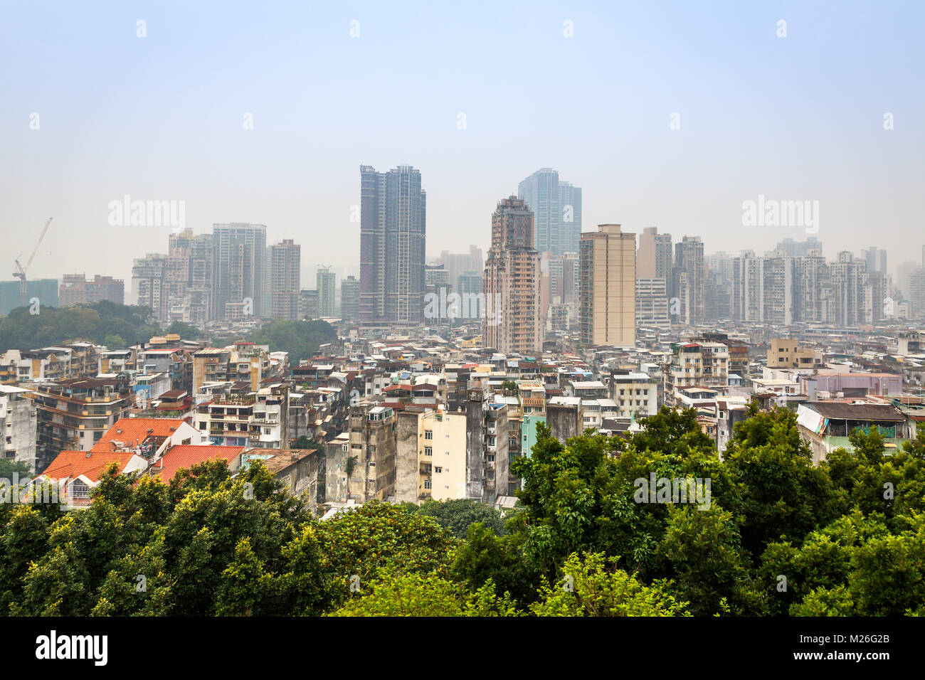 Macau Innenstadt Panorama mit Slums und hohen Wohn Gebäuden mit Bäumen im Vordergrund, China Stockfoto